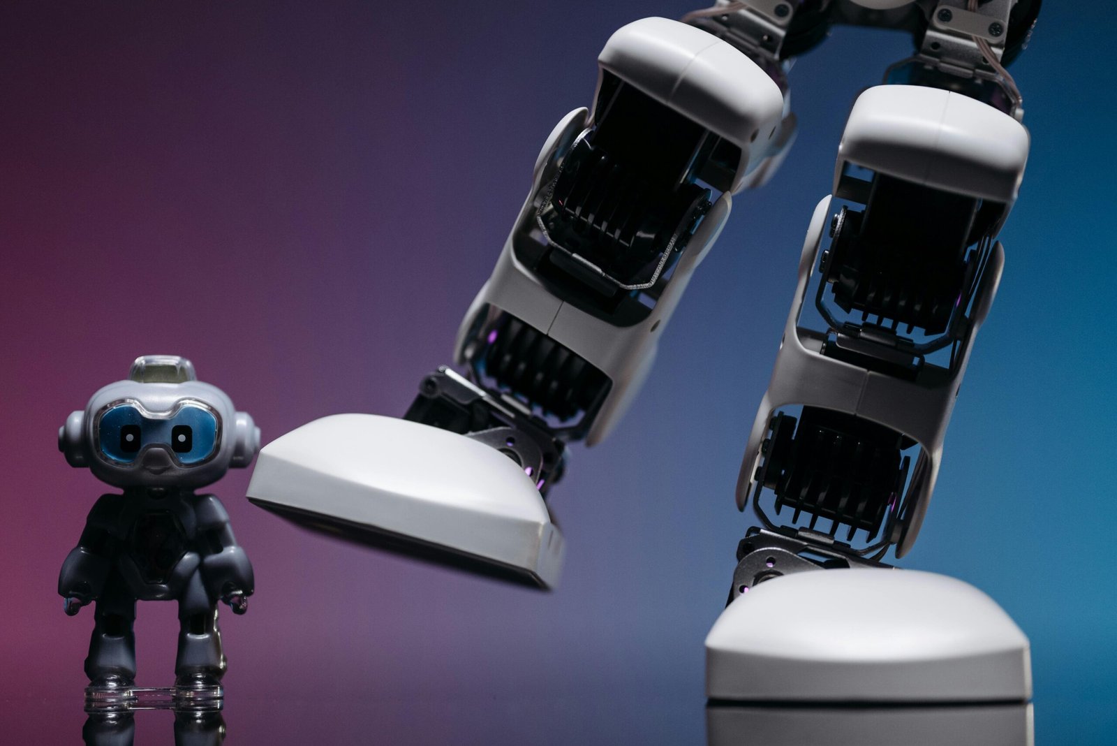 Close-up of small robot toy and large robotic leg in a moody studio setting.